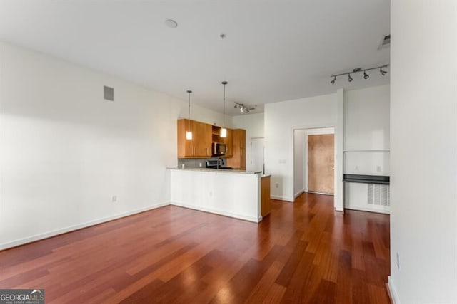 kitchen featuring decorative light fixtures, dark hardwood / wood-style floors, kitchen peninsula, and track lighting