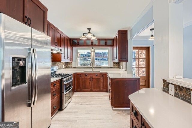 kitchen with pendant lighting, backsplash, sink, light wood-type flooring, and stainless steel appliances