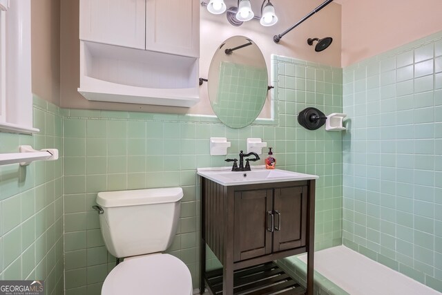 bathroom featuring a tile shower, vanity, tile walls, and toilet