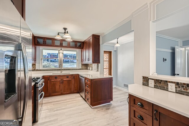 kitchen with appliances with stainless steel finishes, a healthy amount of sunlight, crown molding, sink, and hanging light fixtures