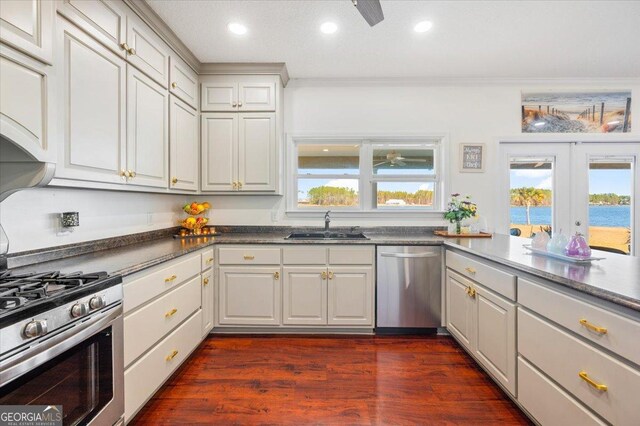 kitchen with appliances with stainless steel finishes, french doors, sink, a water view, and white cabinetry