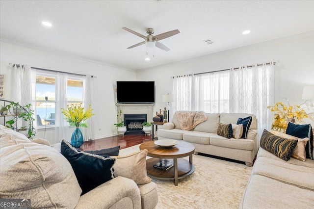 living area featuring visible vents, a healthy amount of sunlight, light wood-style flooring, and crown molding