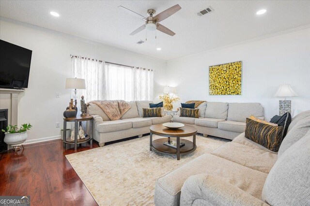 living room with hardwood / wood-style floors, ceiling fan, and ornamental molding