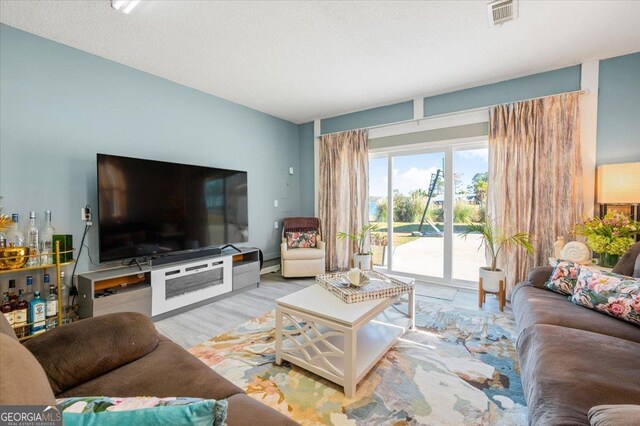 living room featuring a textured ceiling and light wood-type flooring