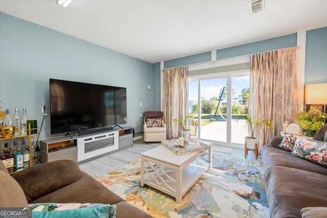 living room featuring visible vents, a textured ceiling, and wood finished floors