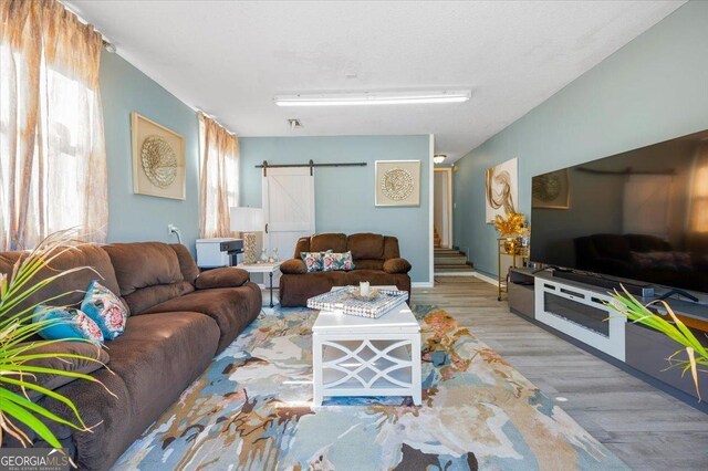 living room with a barn door and hardwood / wood-style flooring