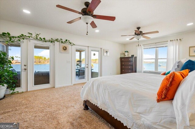 bedroom featuring light carpet, access to outside, french doors, a water view, and ceiling fan