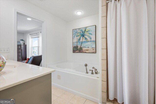 bathroom with vanity, a textured ceiling, tile patterned floors, and a bathtub