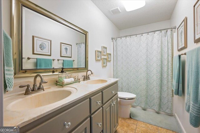 bathroom with tile patterned floors, vanity, toilet, and a textured ceiling