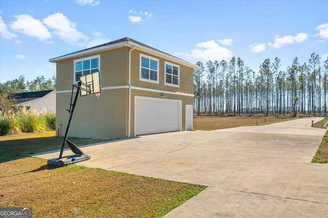 view of side of home featuring stucco siding, a lawn, concrete driveway, and an attached garage