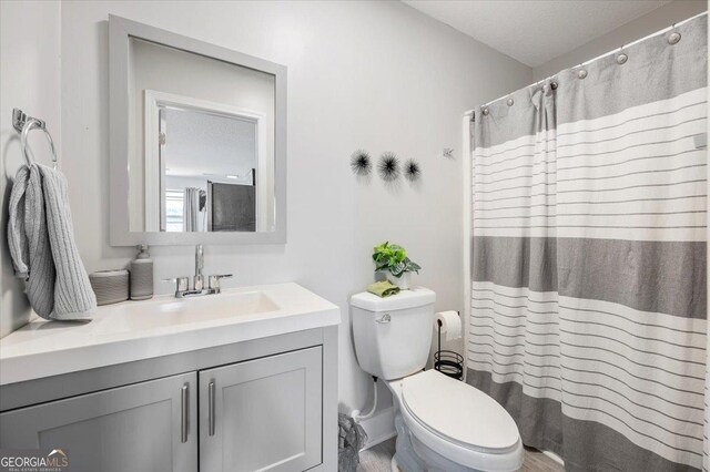 bathroom with a textured ceiling, vanity, and toilet