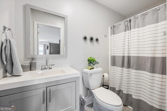 bathroom featuring a shower with shower curtain, toilet, and vanity