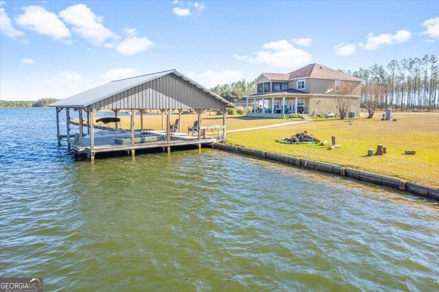 view of dock with a lawn and a water view