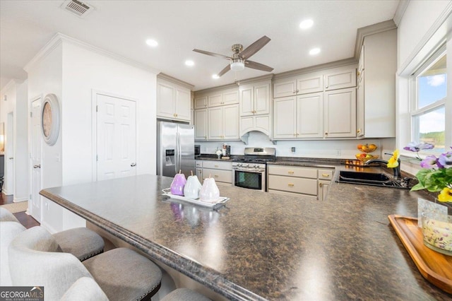 kitchen featuring sink, a breakfast bar area, ceiling fan, ornamental molding, and stainless steel appliances