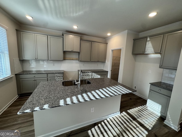 kitchen featuring gray cabinets, sink, an island with sink, and dark stone counters