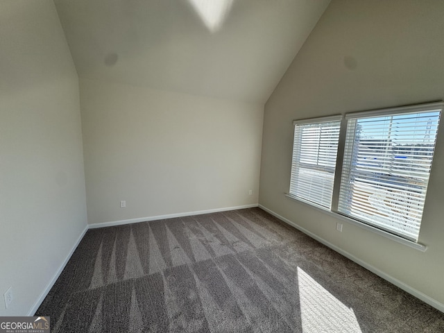 empty room featuring dark colored carpet and lofted ceiling