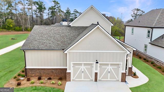 view of front of house with driveway, a front lawn, an attached garage, and a shingled roof