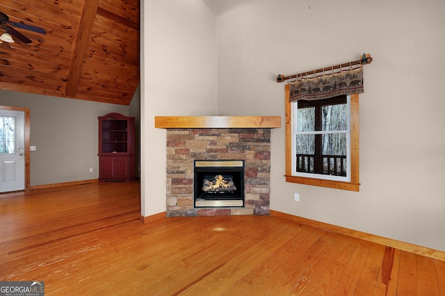 unfurnished living room featuring ceiling fan, wooden ceiling, lofted ceiling with beams, a fireplace, and hardwood / wood-style flooring