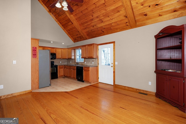 kitchen featuring high vaulted ceiling, black appliances, sink, decorative backsplash, and light hardwood / wood-style floors