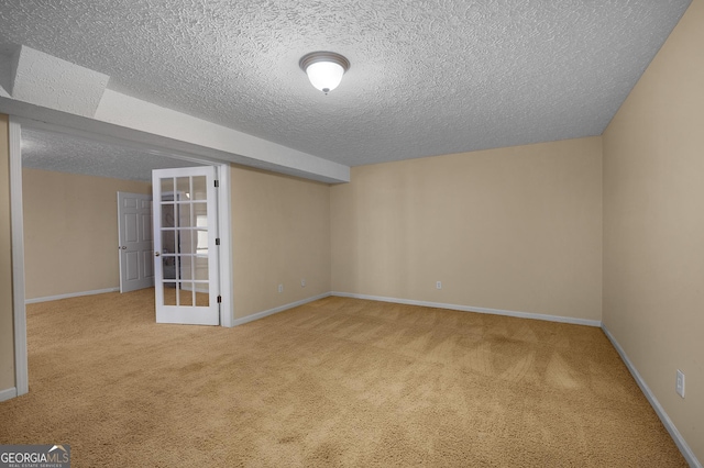 carpeted empty room with a textured ceiling and french doors