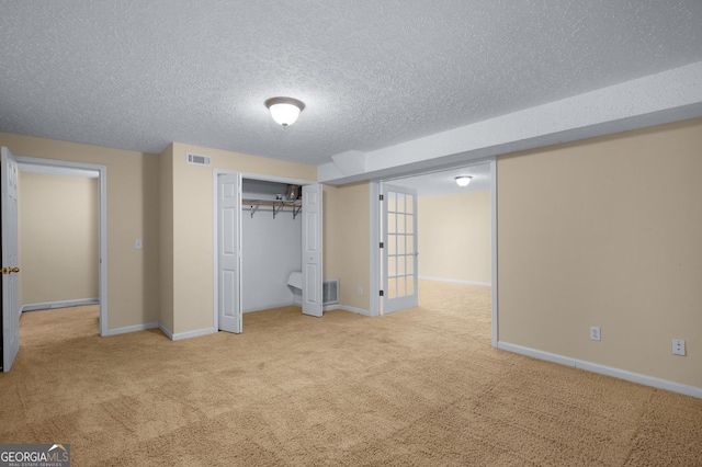 unfurnished bedroom with a textured ceiling, light carpet, and a closet