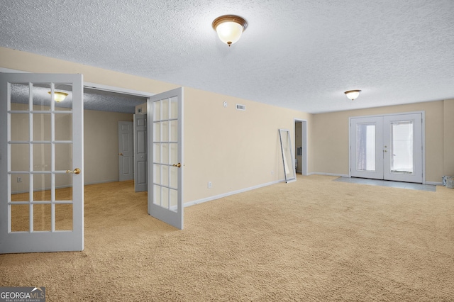 spare room featuring carpet floors, a textured ceiling, and french doors