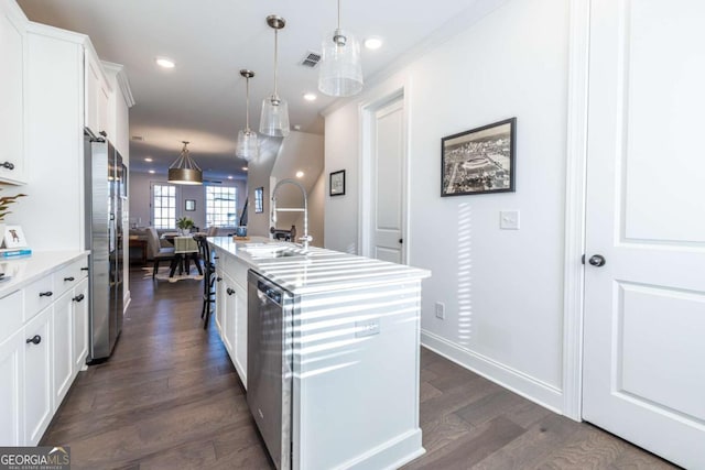 kitchen with white cabinetry, sink, stainless steel appliances, an island with sink, and decorative light fixtures