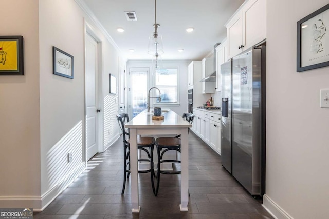 kitchen featuring a kitchen island with sink, white cabinets, pendant lighting, and appliances with stainless steel finishes