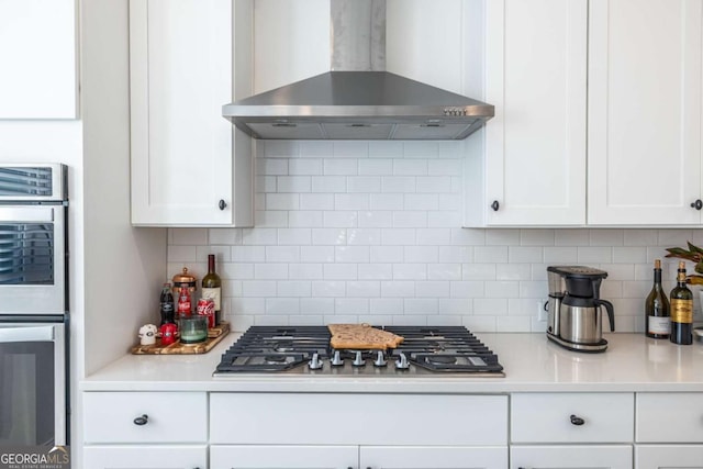 kitchen featuring backsplash, white cabinets, and wall chimney range hood