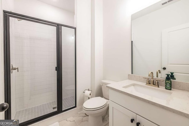 bathroom featuring a shower with door, vanity, and toilet