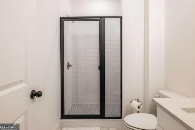 bathroom with a shower with door, vanity, and toilet