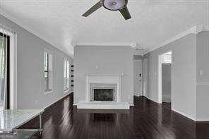 unfurnished living room with a fireplace, dark wood-type flooring, and ornamental molding