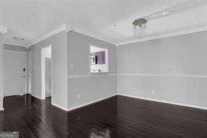 empty room with hardwood / wood-style flooring and crown molding