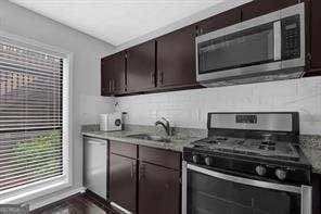 kitchen with dark brown cabinetry, sink, dark hardwood / wood-style floors, and appliances with stainless steel finishes