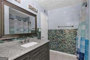 bathroom featuring curtained shower, tile patterned flooring, and vanity