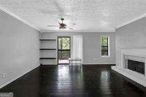 unfurnished living room featuring a textured ceiling, dark hardwood / wood-style floors, ceiling fan, and crown molding