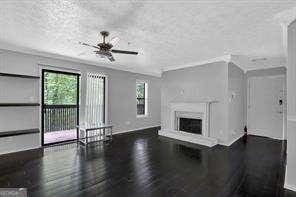 unfurnished living room with dark hardwood / wood-style floors, ceiling fan, and ornamental molding