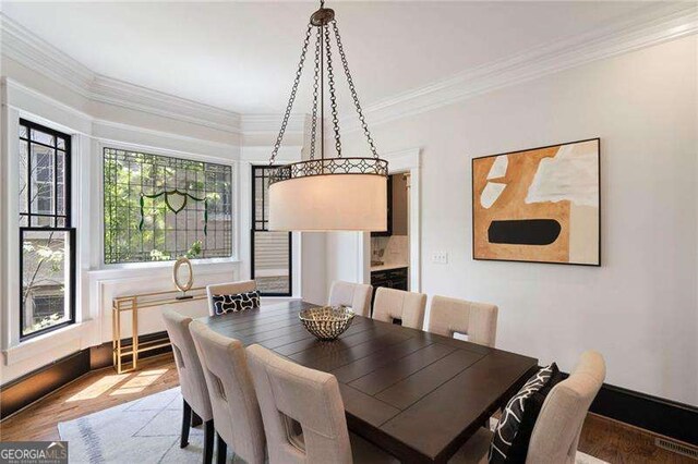 dining room with hardwood / wood-style flooring and crown molding