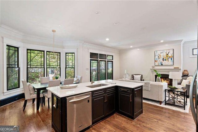 kitchen featuring dishwasher, a kitchen island with sink, sink, light wood-type flooring, and a wealth of natural light