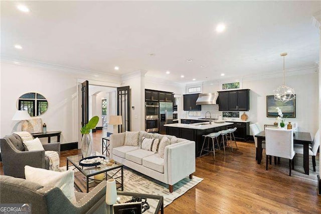 living room with dark hardwood / wood-style floors, a notable chandelier, ornamental molding, and sink