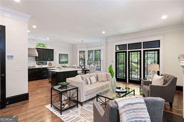 living room with ornamental molding, sink, a wealth of natural light, and light hardwood / wood-style flooring