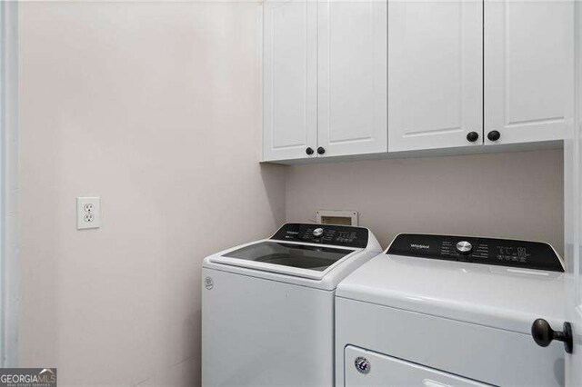 clothes washing area with cabinets and independent washer and dryer