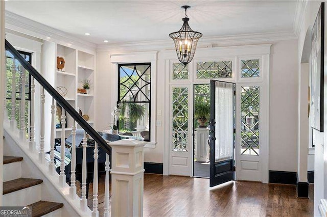 foyer entrance featuring crown molding, french doors, dark wood-type flooring, and an inviting chandelier