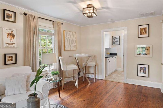 sitting room with crown molding and light hardwood / wood-style floors