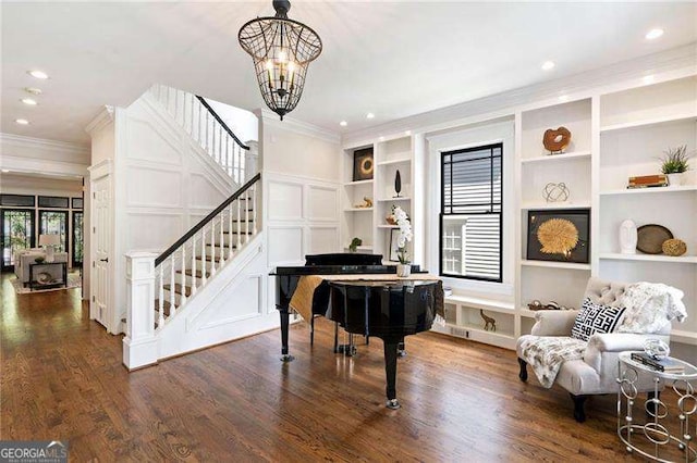 sitting room featuring ornamental molding, dark wood-type flooring, built in features, and a notable chandelier