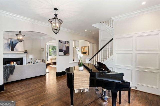 foyer with dark hardwood / wood-style floors, ornate columns, ornamental molding, and an inviting chandelier