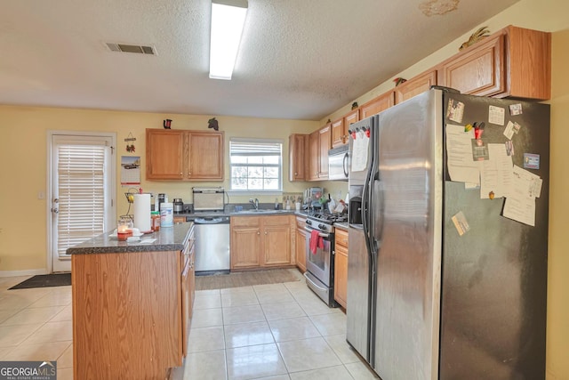 kitchen with sink, light tile patterned floors, a textured ceiling, and appliances with stainless steel finishes