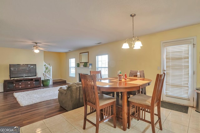 tiled dining area with ceiling fan with notable chandelier