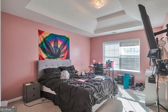 bedroom with a tray ceiling, light carpet, and a textured ceiling