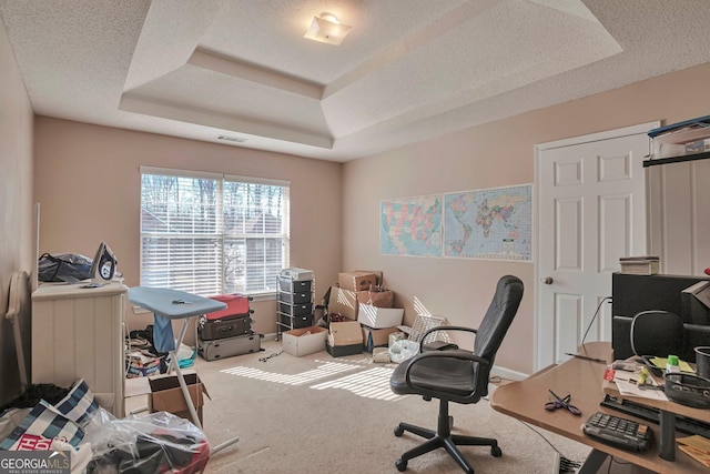 home office featuring a raised ceiling, carpet, and a textured ceiling